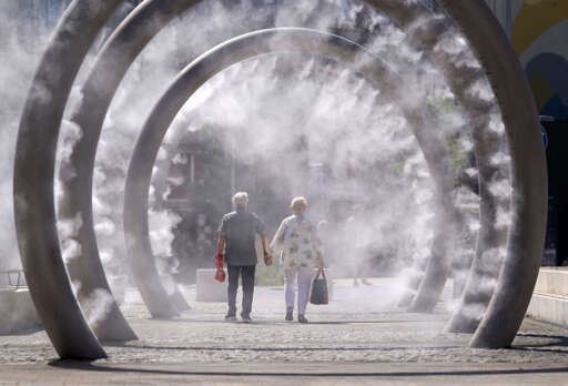 A couple cool off as they walk through a cooling water feature spraying a fine mist in Dover, Kent, as the third heatwave of the summer hits the UK and temperatures expected to remain high into the weekend, on July 11, 2025.